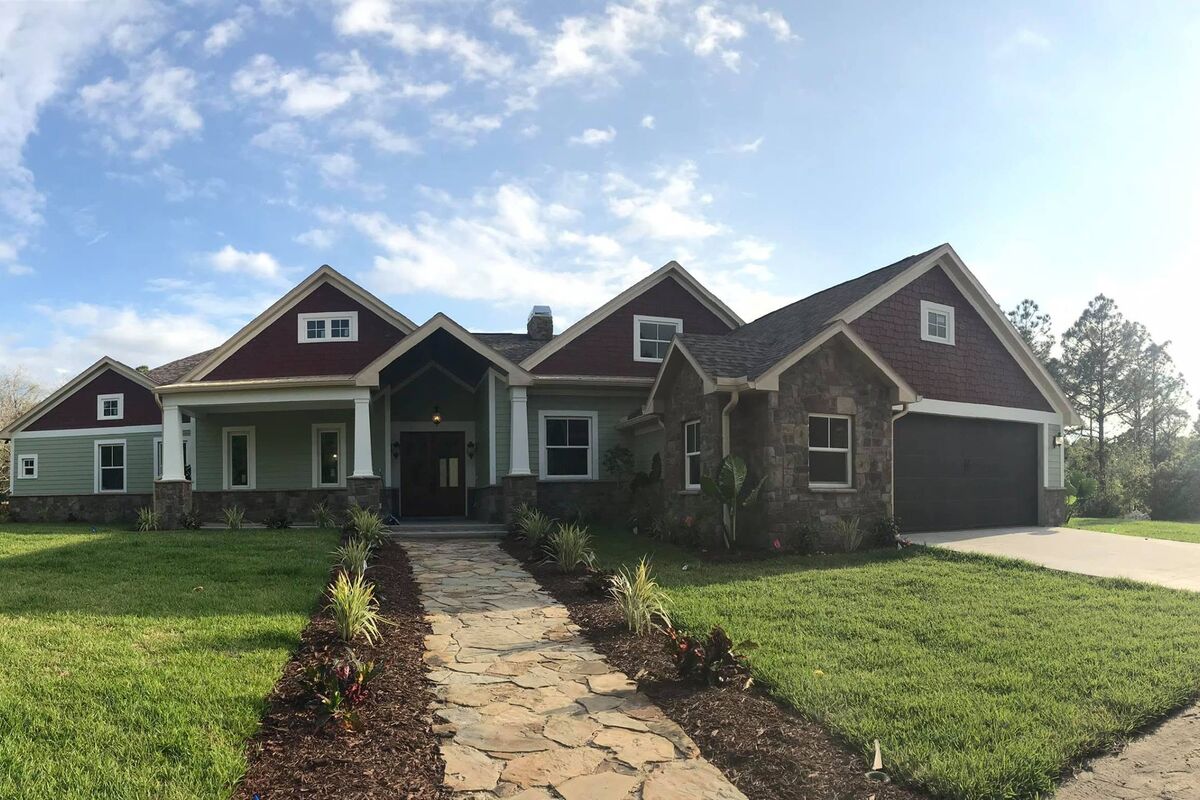 Completed craftsman home with landscaped lawn and stone path