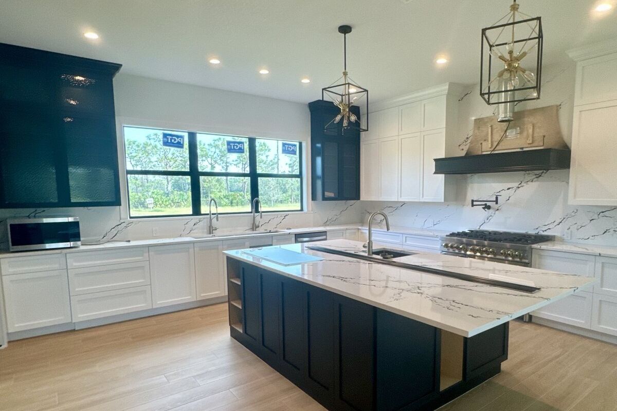 Finished kitchen with a navy island and quartz waterfall counter