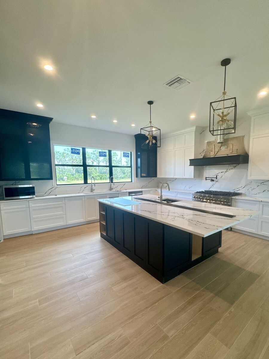 Kitchen with navy island, quartz counters and lantern pendants