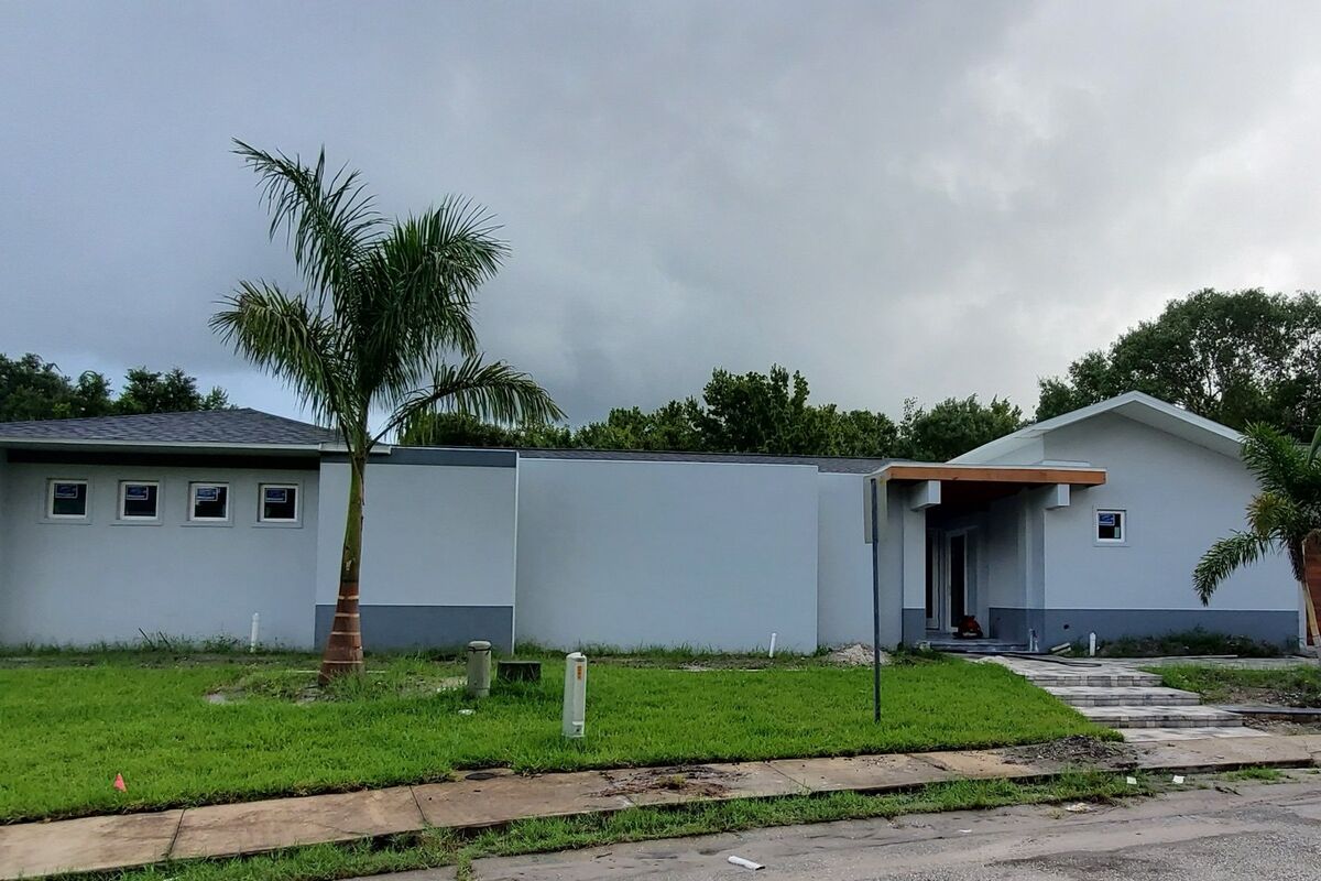 Wide single-story residence with palms and a metal roof