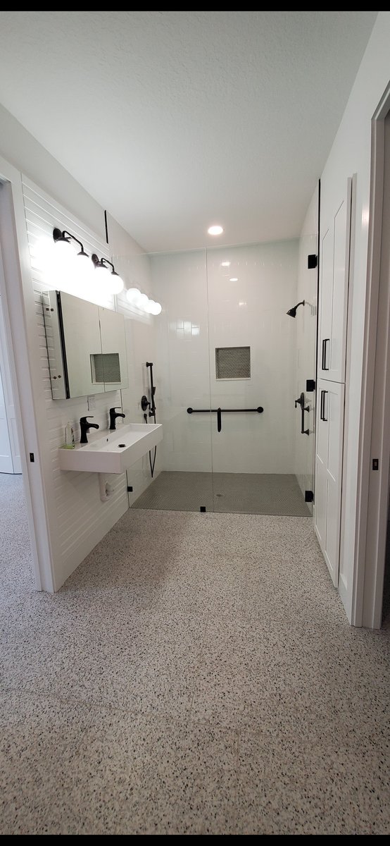 Curbless walk-in shower with terrazzo floor and matte black fittings