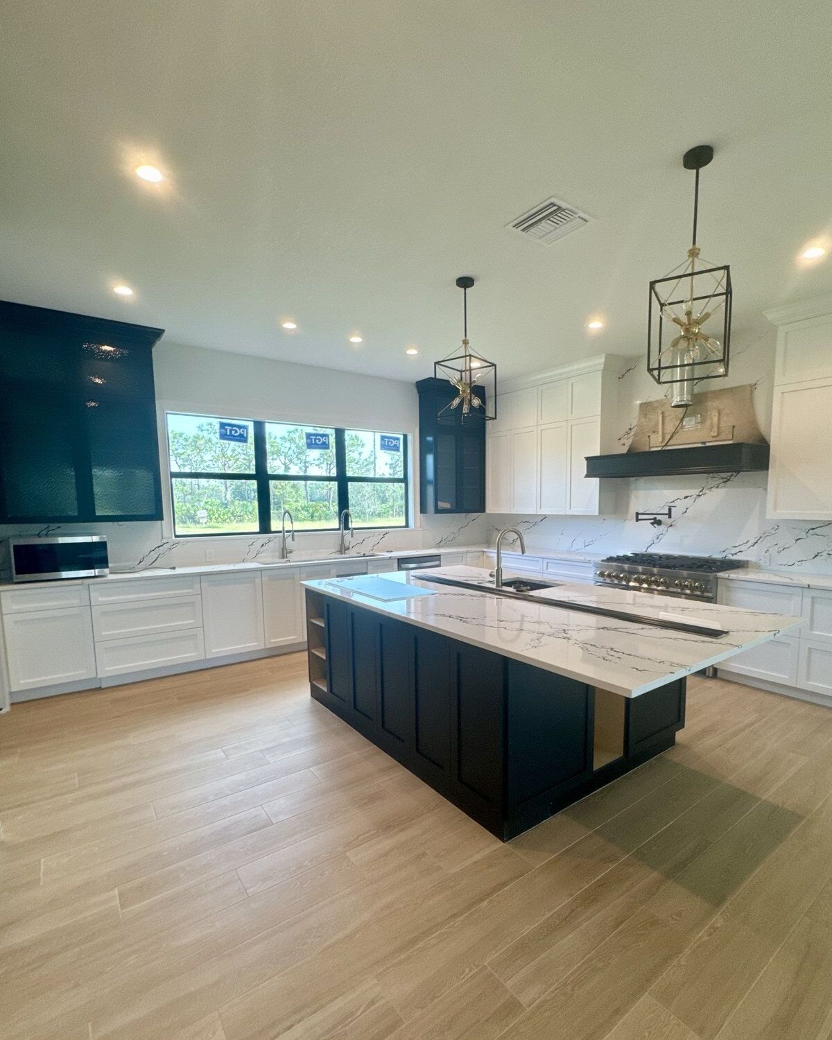 Renovated kitchen with custom cabinetry, quartz counters and a range hood