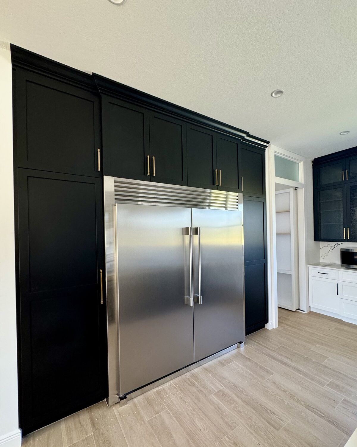 Floor-to-ceiling black millwork with integrated refrigeration